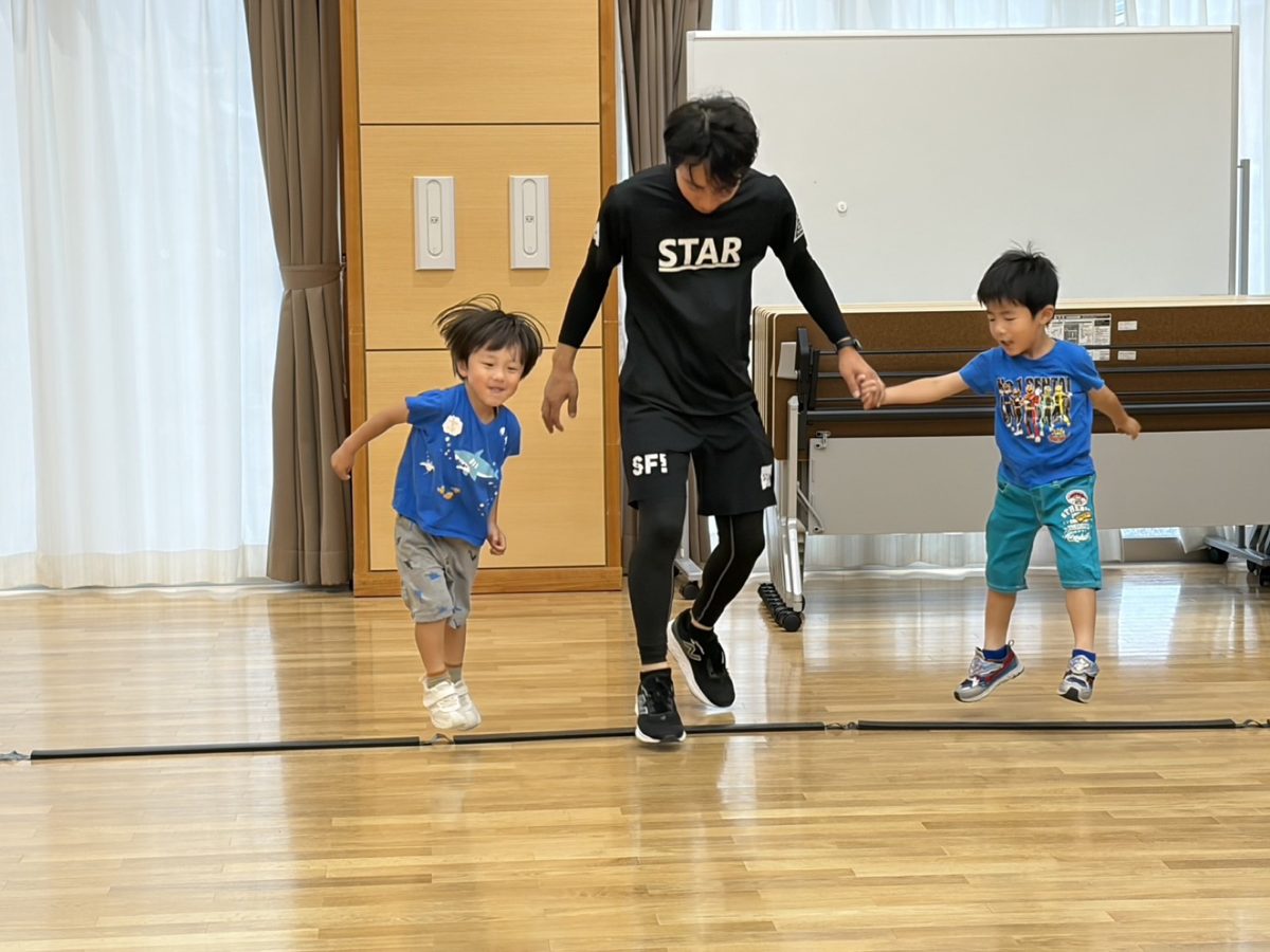 先生と手をつないでジャンプする子どもたち